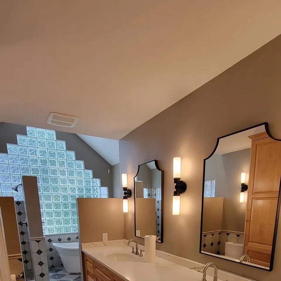 Remodeled bathroom with a double vanity, two arched mirrors and wall sconces after a Cedar Tone remodel