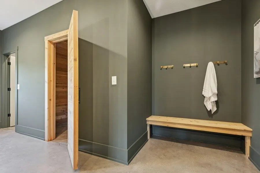 Hallway with light greige walls, white trim and doors, a wood bench and a hardwood floor in a newly finished home.